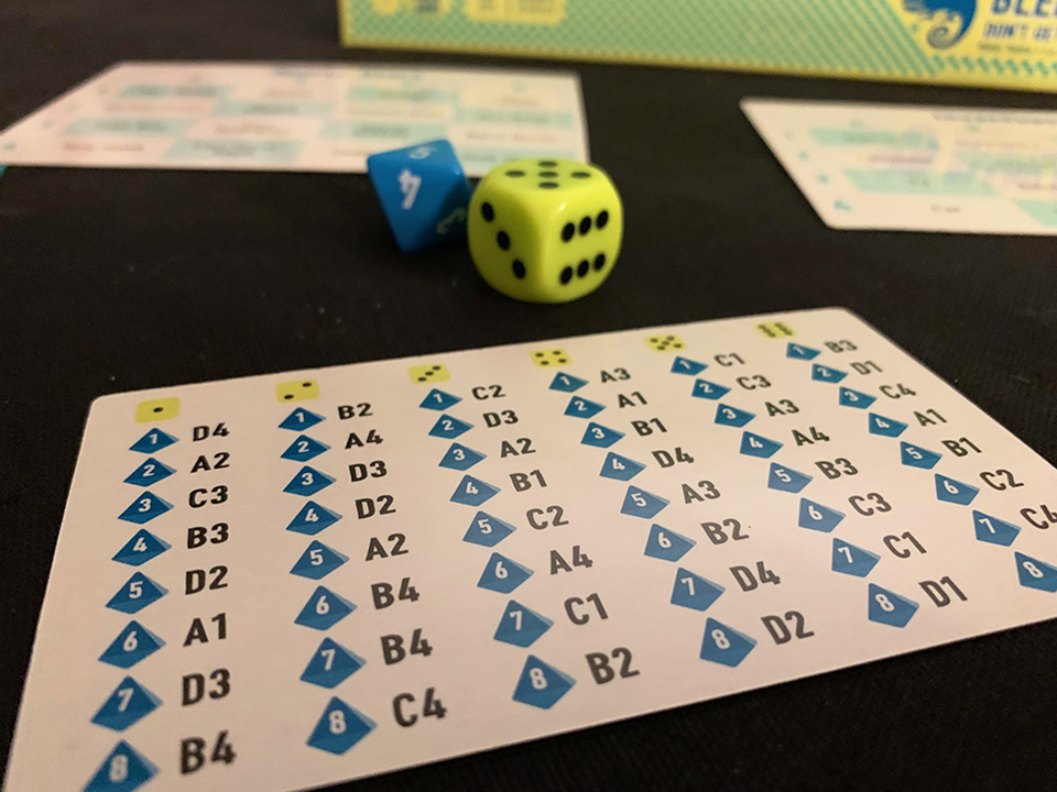 a blue and yellow dice with a grid of letters and numbers 